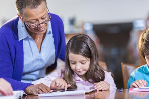 An image showing a teached helping a young student use a tablet