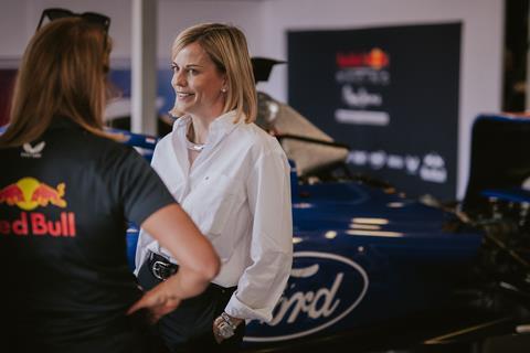 Susie Wolff speaking to a colleague from the Red Bull team in front of a racing car