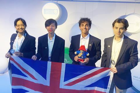 Four students with medals and a union jack flag