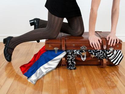 A student closing a suitcase
