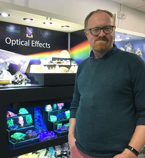 A photo of a man standing in front of a display case of different rocks