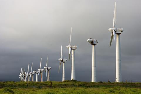 A line of old broken wind turbines under a grey sky