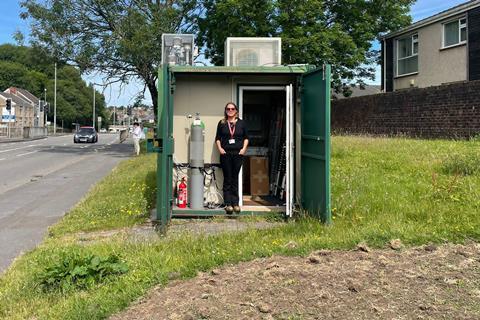 Emma is standing in an outdoor office with equipment inside.