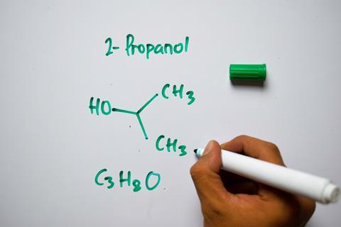 A hand drawing the structure of propanol on a whiteboard