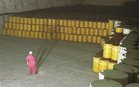 A person observing many yellow waste barrels