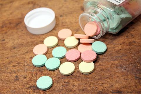 Colourful antacid tablets for stomach problems spilling out from a bottle