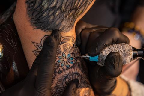 A tattoo artist using blue ink