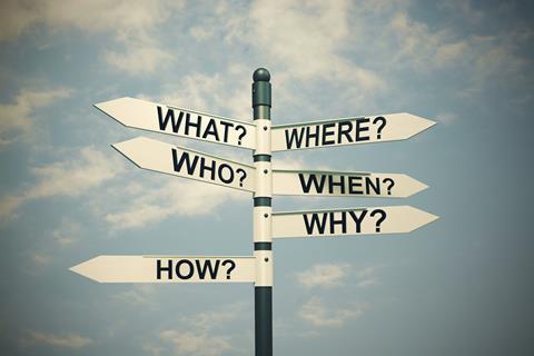 Signpost with question words against a blue sky