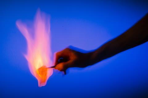 A hand with some burning paper