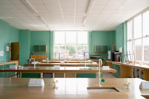 An image showing an empty science classroom, with benches, sinks, sockets and gas taps,, stool on benches