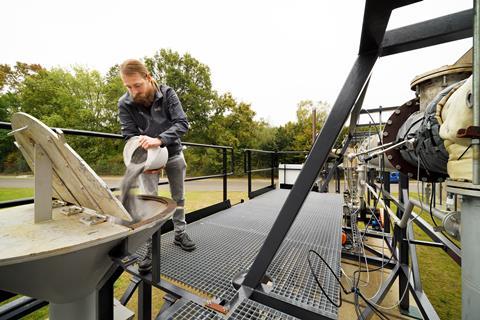 A man pours metal powder into a hopper