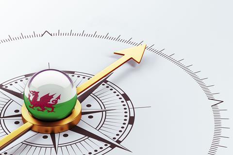 An illustration of a compass with the Welsh flag in the centre