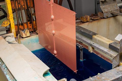 A sheet of galvanised copper is pulled out of a bath of blue copper sulphate