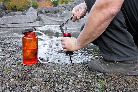 A man using a filtration system to filter water from a river for drinking