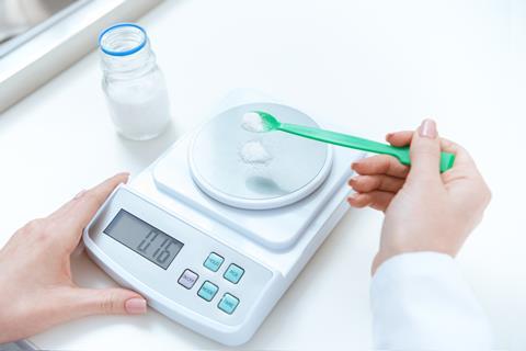 An image of a person weighing out a reagent on a balance scale