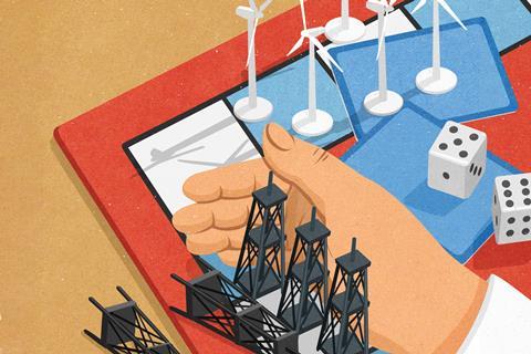A hand sweeps model oil wells from a board game leaving wind turbines behind
