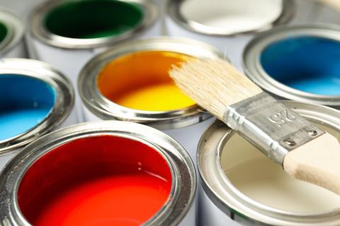 A paintbrush and tins of colourful paints