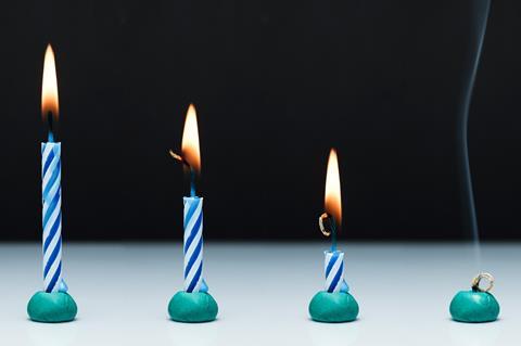 An image showing four stripey blue and white candles, all alight, from left to right, they show the progression of burning