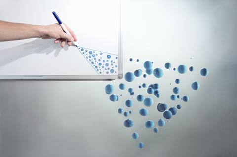 A photo of a hand drawing circles on a whiteboard that turn into blue spheres