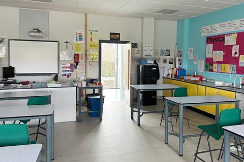 A school science classroom showing desks, the interactive white board and Physics posters on the wall