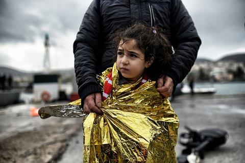An image showing a young migrant girl wrapped in a thermal blanket