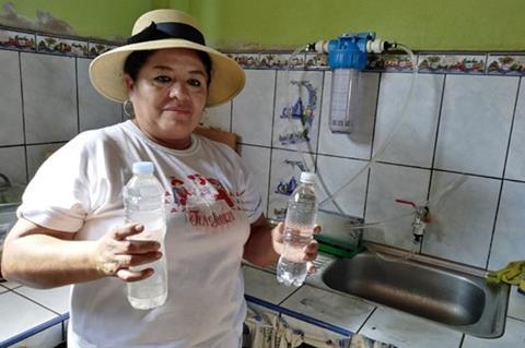 A woman in a kitchen with bottles of cloudy and clear water