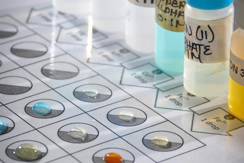Close up of a microscale experiment where drops of metal ion solutions are mixed on a laminated grid