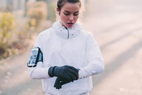 A photo of a woman looking at her smartwatch during a run outdoors