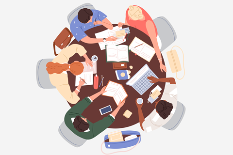 A group of students revising around a table. Some are reading, some are explaining concepts to each other and one is trying a past exam paper.