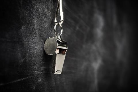 A picture of a silver whistle hanging on a blackboard