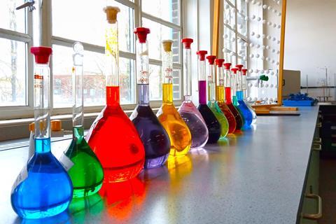 Glass flasks containing different coloured liquids on a bench in a science classroom
