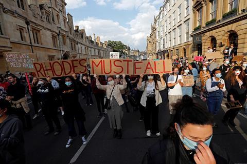 People at a protest with placards which says Rhodes Must Fall