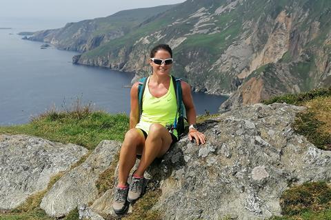Orla Casby sitting on some rocks with a view of a wild rocky coastline behind her