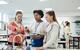 A photograph of two students and their teacher discussing a chemistry experiment, with a variety of apparatus set up in front of them