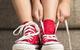 Child tying shoelaces on red American sneakers