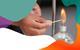 A hand is lighting a spirit burner with a match and there is a colourful border around the edge of the image