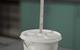 Thermometer stuck through hole in lid of polystyrene cup