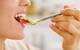 picture of a woman tasting different fruits on a spoon