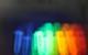 Blue, green, yellow, orange and red light visible from luminescent test tubes against a black background
