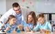 Teacher leaning over three learners who are pouring liquids into chemistry glassware.
