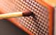 A close-up photograph of a brown match head held against the side of a match box ready to be struck