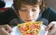 picture of a boy smelling a slice of pizza