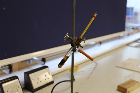 Equipment set up in a school laboratory for an experiment simulating the fractional distillation of crude oil, with a side-arm test tube, a thermometer and a delivery tube