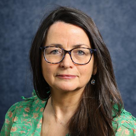 A photo of Wendy Winnard wearing glasses and a green blouse with pink flowers.