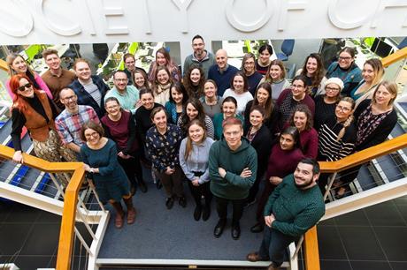 Members of the Education team at the RSC stand on steps inside the RSC offices, posing for a group photograph taken from above.